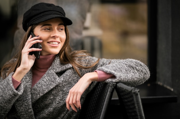 Vrouw met telefoon zitten buiten café