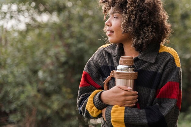 Vrouw met thermos terwijl kamperen buiten met kopie ruimte