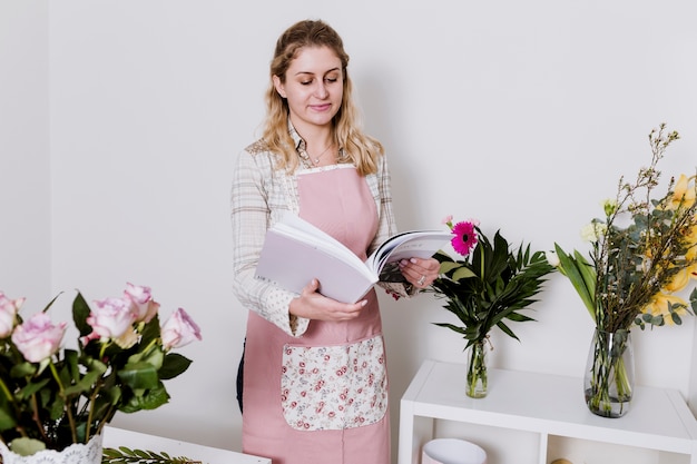 Gratis foto vrouw met tijdschrift in bloemenwinkel