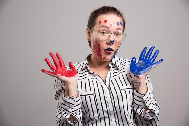 Vrouw met verf op haar gezicht en bril op grijs