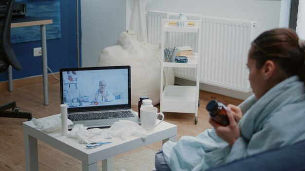 Vrouw met verkoudheid en griep die videogesprek gebruikt voor telegeneeskunde
