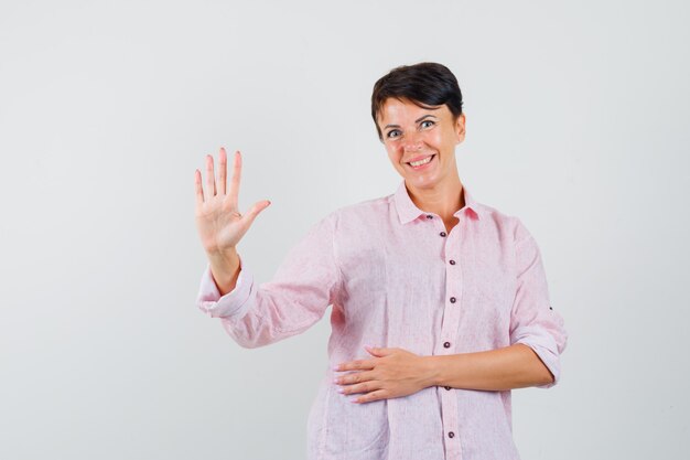 Vrouw met vijf vingers in roze shirt en op zoek vrolijk, vooraanzicht.