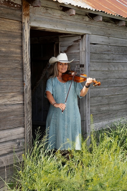 Gratis foto vrouw met viool maakt zich klaar voor countrymuziekconcert