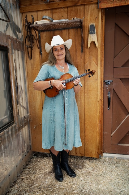 Gratis foto vrouw met viool maakt zich klaar voor countrymuziekconcert