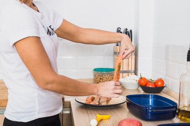 Vrouw met vis plak in de keuken