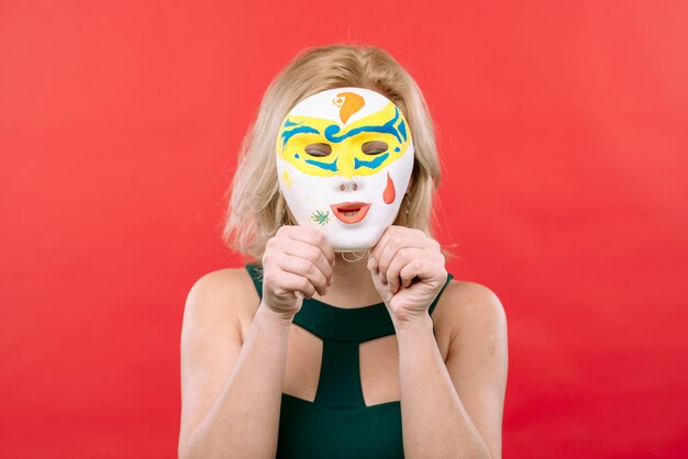 Vrouw met wit Carnaval-masker in handen