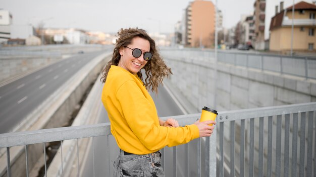 Vrouw met zonnebril die zich op een brug bevindt