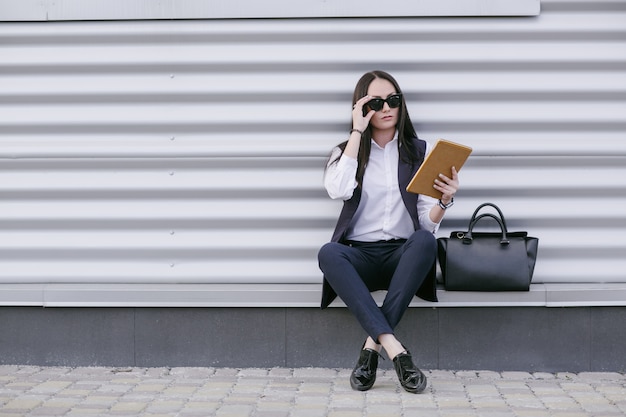 Vrouw met zonnebril en een oranje tablet in de hand