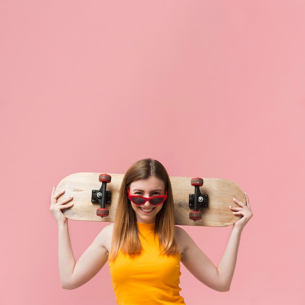 Vrouw met zonnebril en skateboard met exemplaar-ruimte