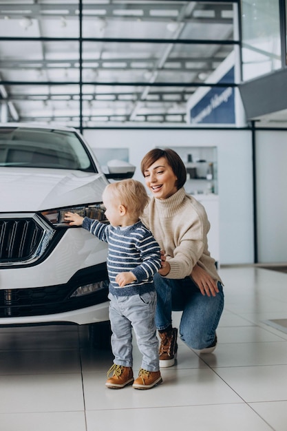 Vrouw met zoontje die een auto kiest in een autosalon