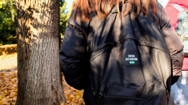 Vrouw met zwarte rugzak op een straat in de herfst, achteraanzicht