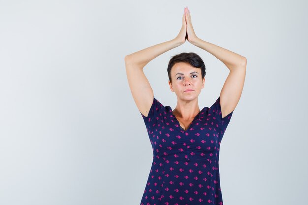 Vrouw namaste gebaar boven het hoofd in jurk tonen en hoopvol kijkt