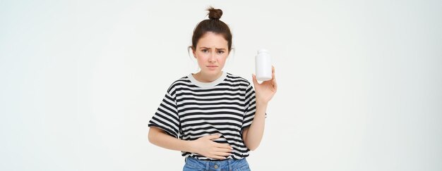 Vrouw neemt pijnstillers pillen voor maagpijn menstruatiepijn houdt hand op buik toont fles met