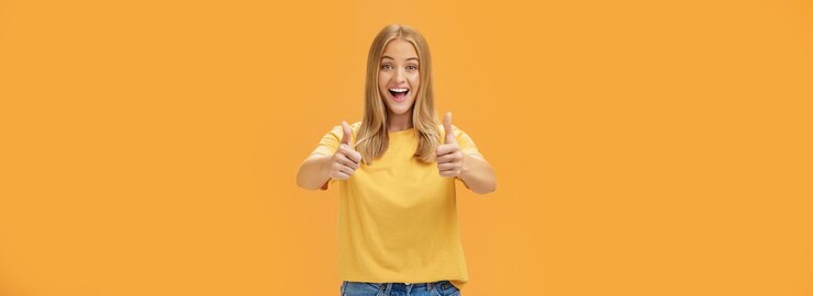 Gratis Foto vrouw ondersteunt met opgeheven duimen omhoog en vermaakt vrolijke glimlach tonen positieve houding uitdrukken