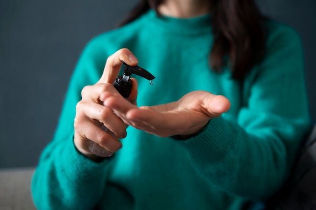 Vrouw ontsmet haar handen thuis tijdens quarantaine