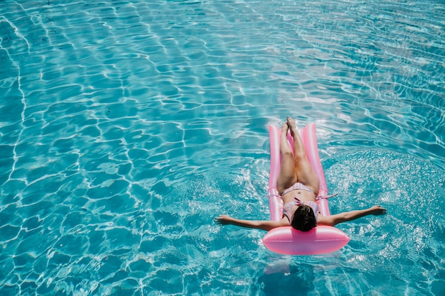 Vrouw ontspannen op matras in zwembad