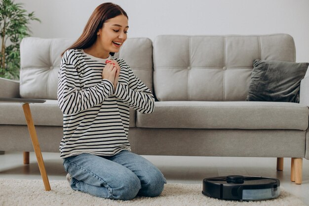 Gratis foto vrouw ontspannen terwijl robotstofzuiger de kamer opruimt