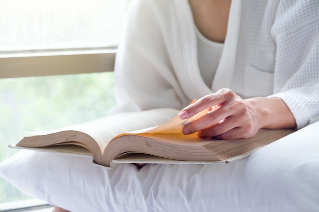 Vrouw ontspant en leest op het bed met oud boek