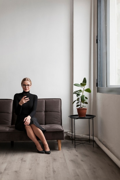 Vrouw op bank mobiel gebruiken