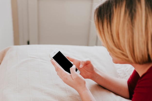 Gratis foto vrouw op bed met behulp van smartphone