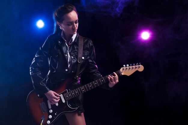 Vrouw op het podium met een gitaar en riem