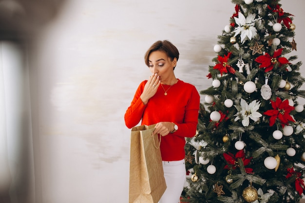 Vrouw op Kerstmis met giften door Kerstmisboom