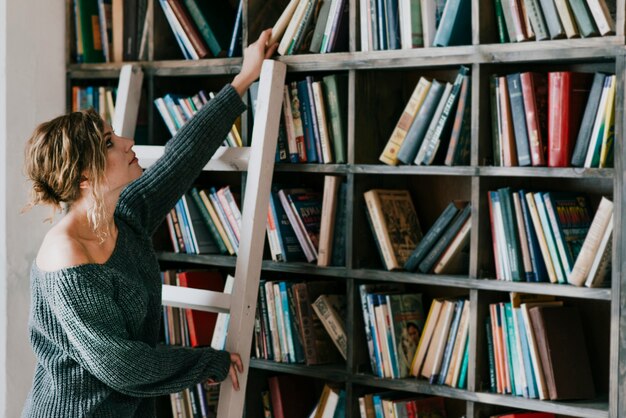 Vrouw op ladder die boek neemt