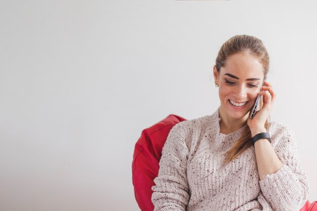 Vrouw op leunstoel praten over de telefoon