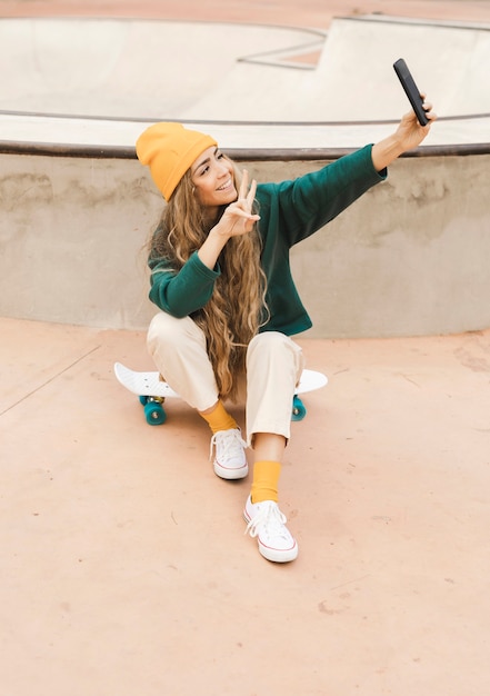 Gratis foto vrouw op skateboard dat selfie neemt