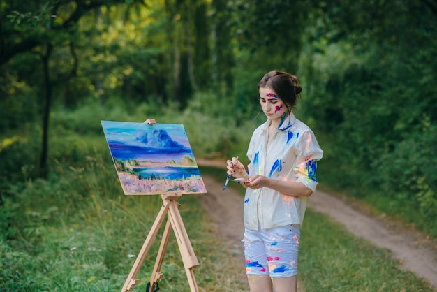 Vrouw op zoek naar haar hand terwijl het houden van een penseel naast een canvas