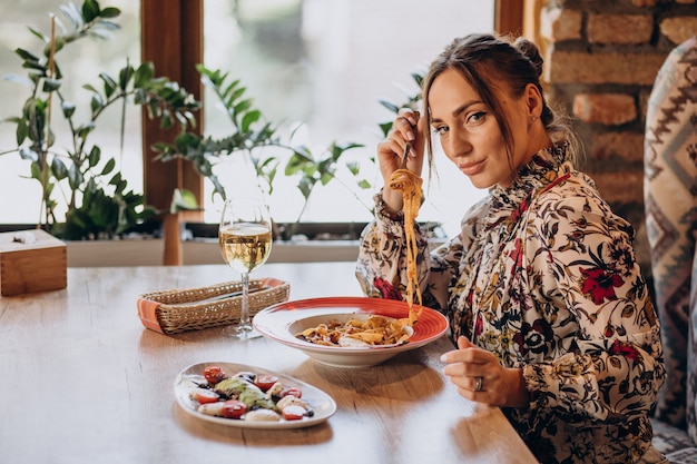 Gratis foto vrouw pasta eten in een italiaans restaurant