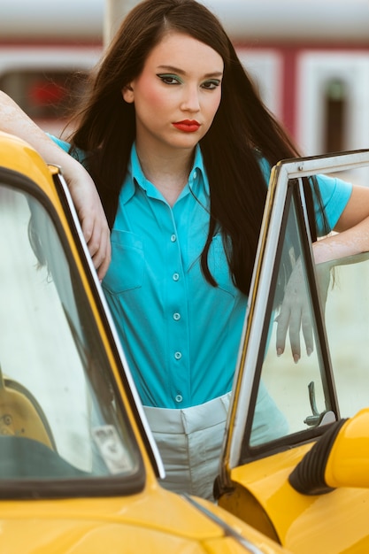 Gratis foto vrouw poseren in retro stijl naast auto