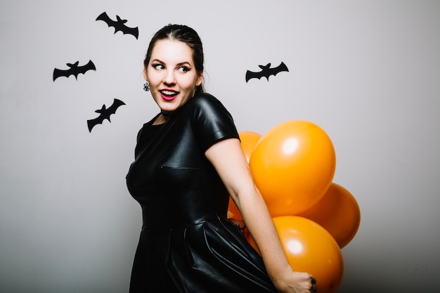 Gratis foto vrouw poseren met ballonnen in halloween decoratie