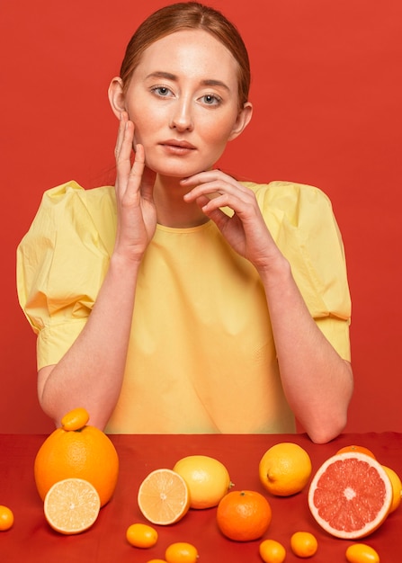 Gratis foto vrouw poseren met een arrangement van citrusvruchten