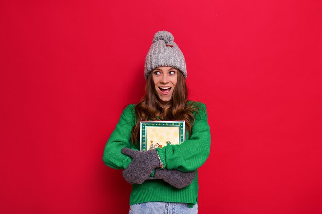 Vrouw poseren met winter muts en handschoenen met een kerstcadeau