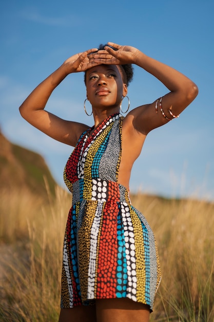 Gratis foto vrouw poserend in een dorre omgeving terwijl ze inheemse afrikaanse kleding draagt