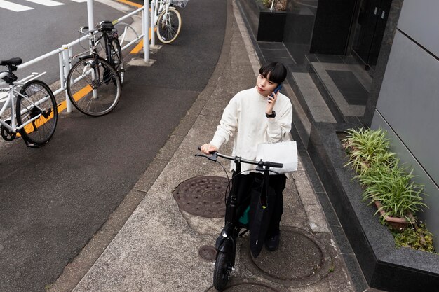 Vrouw praten aan de telefoon en het gebruik van elektrische fiets in de stad