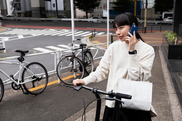Vrouw praten aan de telefoon en het gebruik van elektrische fiets in de stad