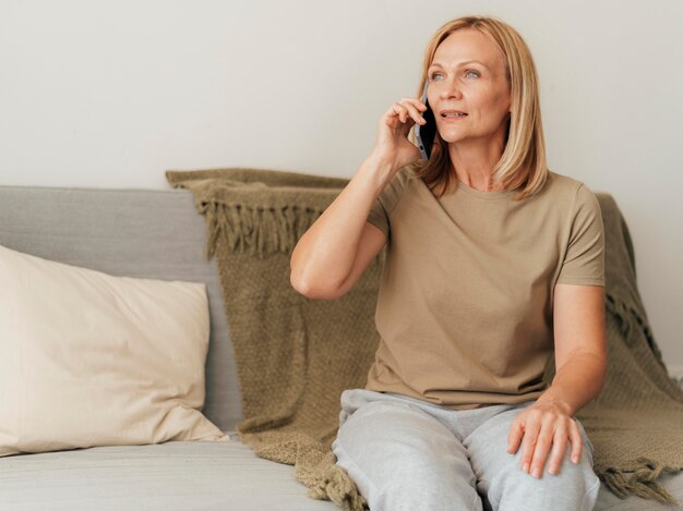 Vrouw praten aan de telefoon thuis tijdens quarantaine