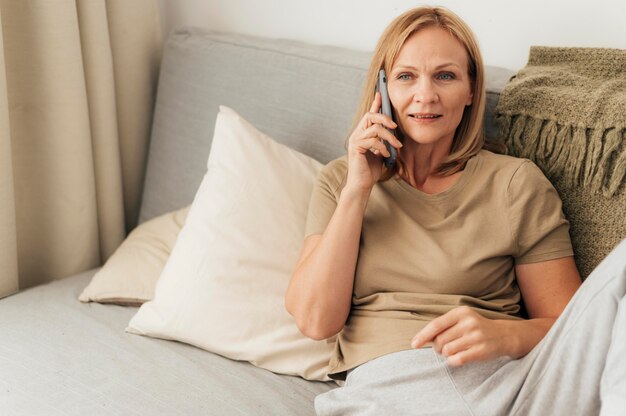 Vrouw praten aan de telefoon tijdens quarantaine thuis