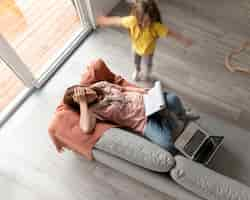 Gratis foto vrouw probeert thuis op laptop te werken terwijl haar kinderen rondrennen