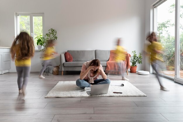 Vrouw probeert thuis op laptop te werken terwijl haar kinderen rondrennen