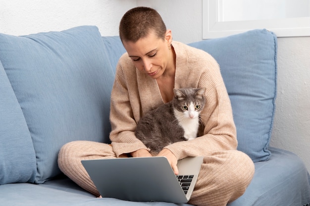 Gratis foto vrouw probeert thuis te werken met haar kat