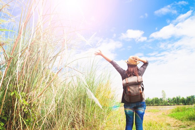 Vrouw reiziger duwen handen en ademhaling in het veld van gras en blauwe lucht, wanderlust reis concept, ruimte voor tekst
