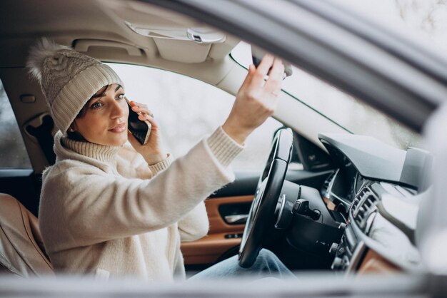 Vrouw rijdt in de auto en gebruikt de telefoon