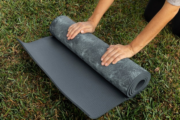 Gratis foto vrouw rollende yogamat op het gras