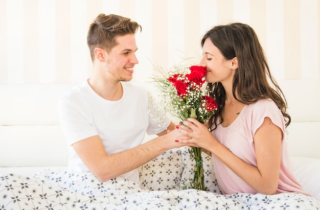 Gratis foto vrouw ruikend boeket ontvangen van de mens