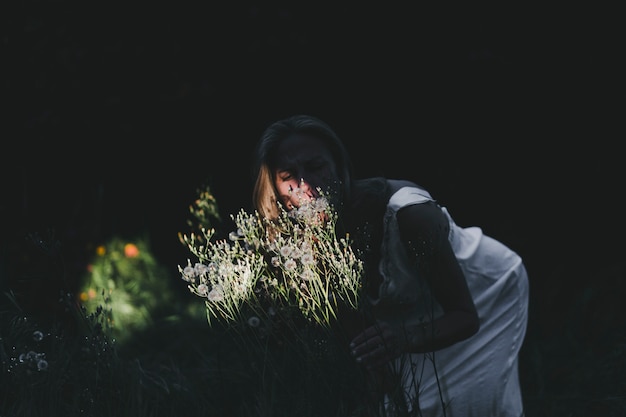 Gratis foto vrouw ruikende veld bloemen