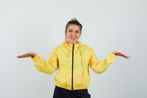 Vrouw schalen gebaar maken in sport pak en op zoek vrolijk, vooraanzicht.