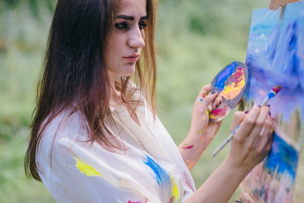 Vrouw schilderen van een foto in het midden van de natuur